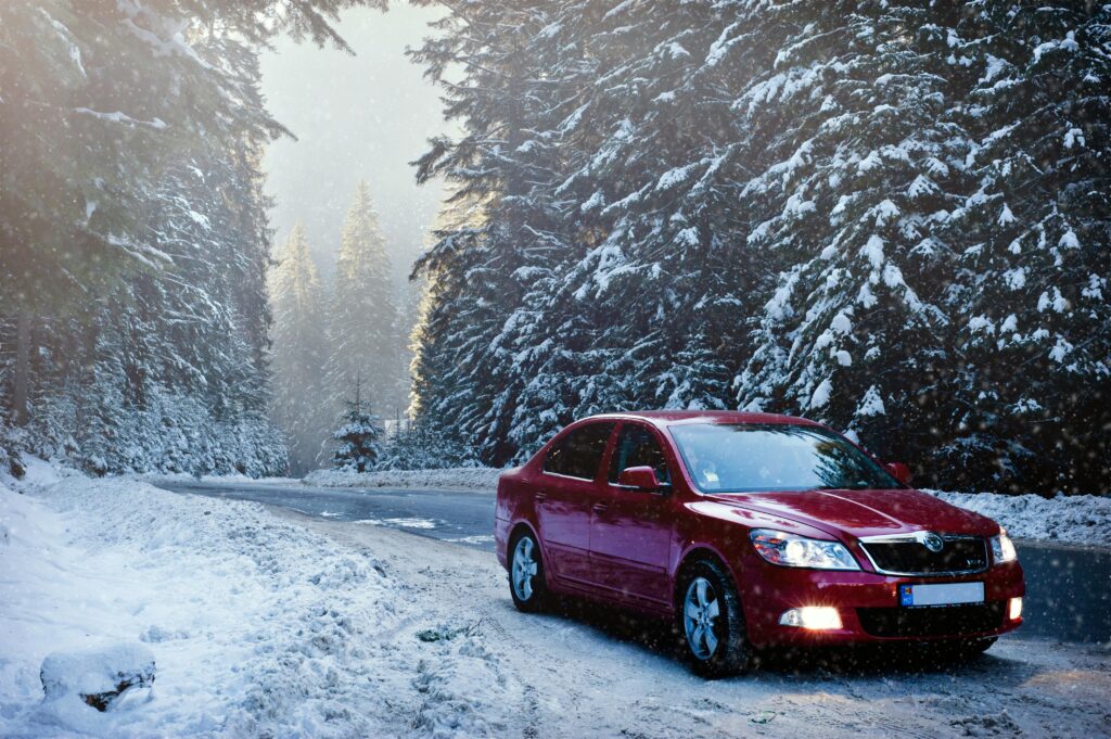 pexels photo 376361 376361 A red car drives along a snowy forest road in winter, surrounded by frosty trees.