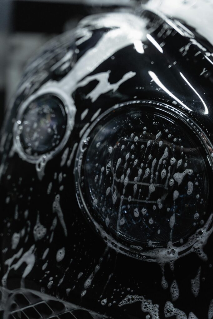 pexels photo 6872149 6872149 A detailed close-up of a car headlight covered with soap suds during a wash.